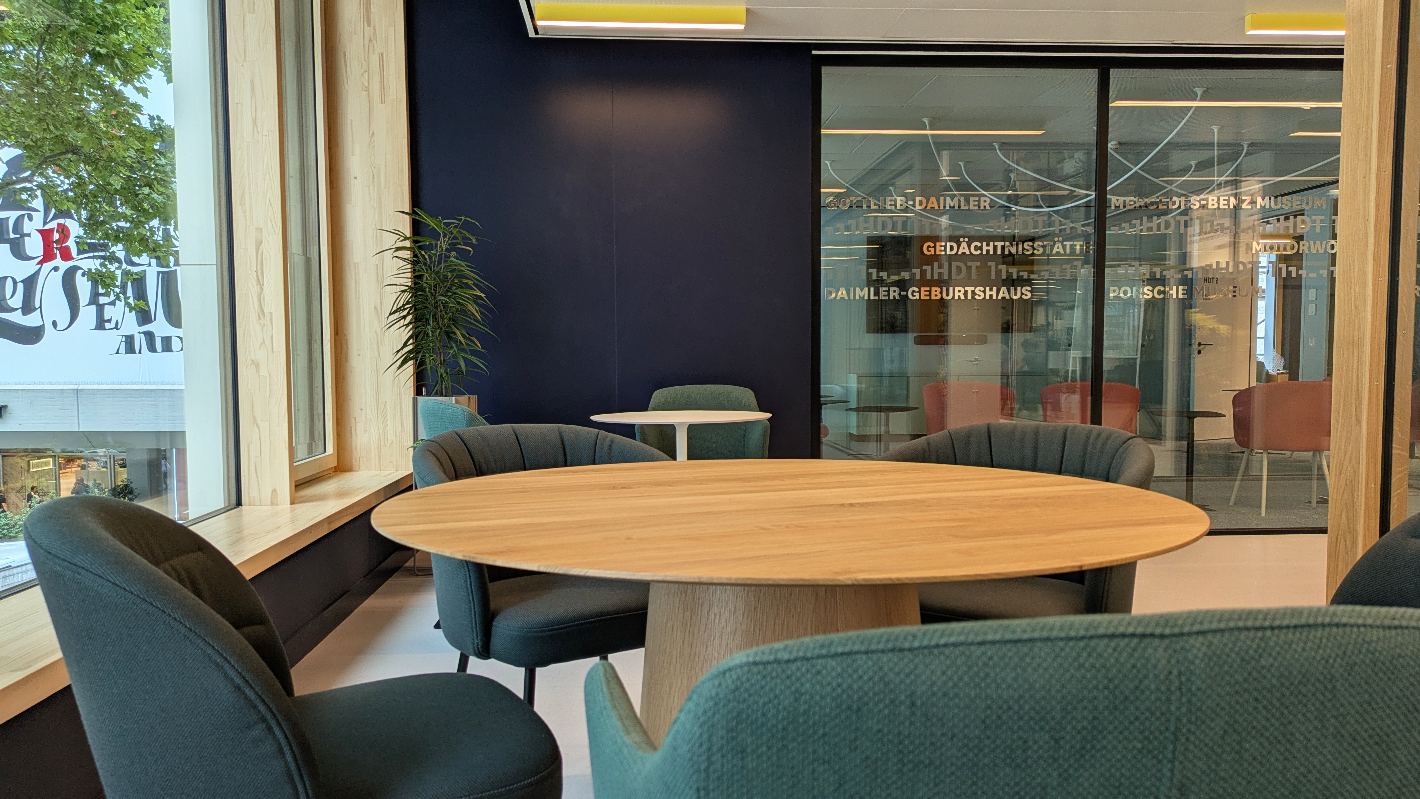 Sitzgruppe in E1, Fünf Sessel stehen um einen runden Tisch in Holzoptik.