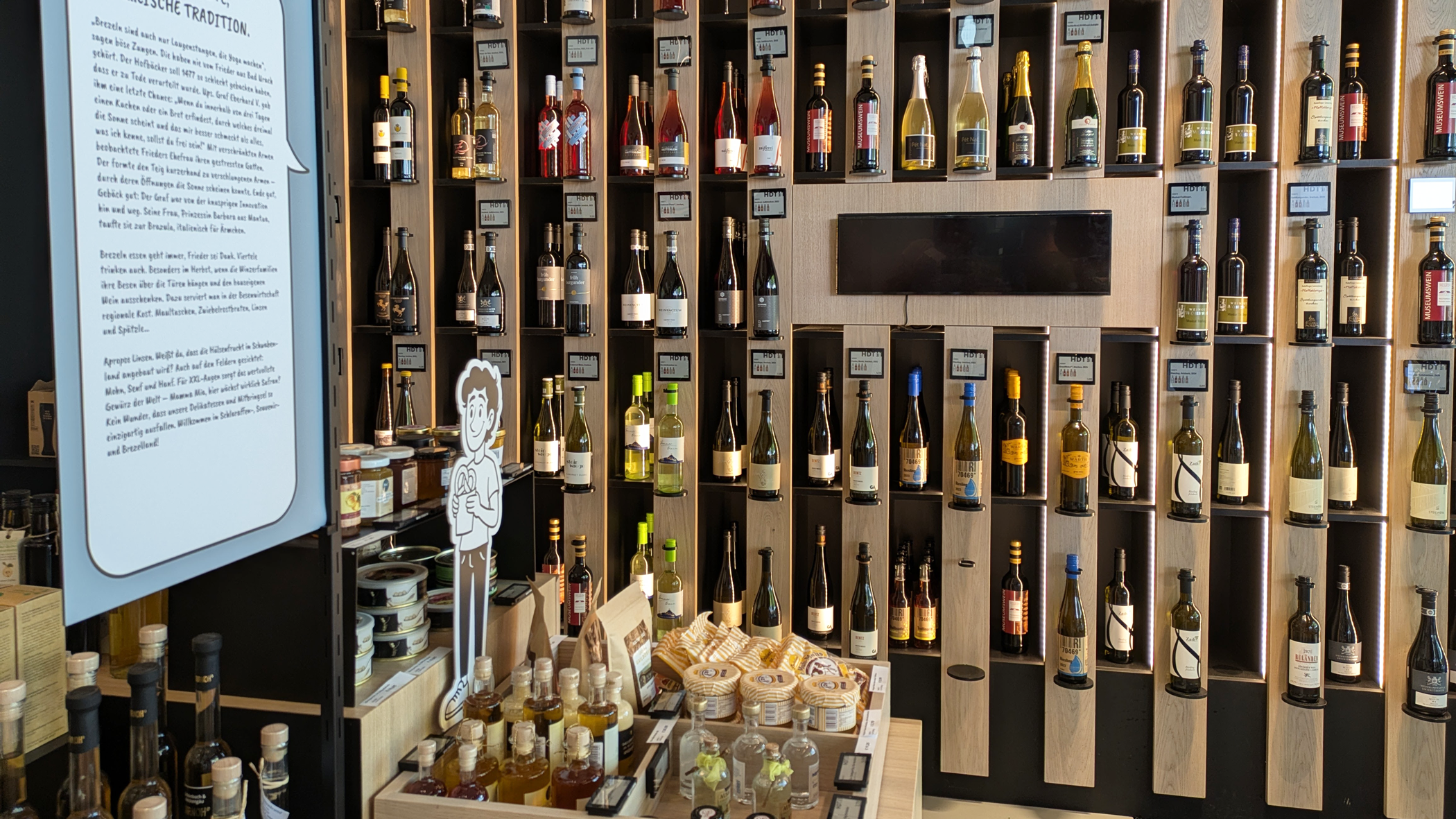 Weinregal und Auslage mit Produkte aus dem Food-Bereich, wie Öle, Bonbons, Marmeladen und Konserven.