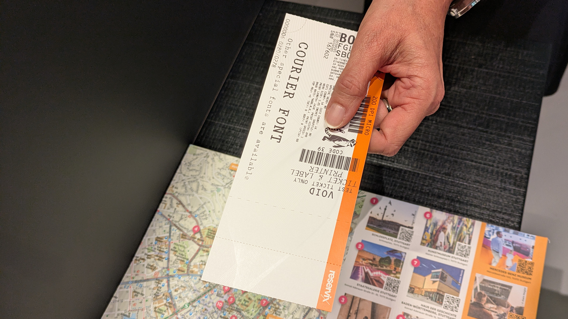 Die Person am Counter überreicht der betrachtenden Person ein Hardticket.