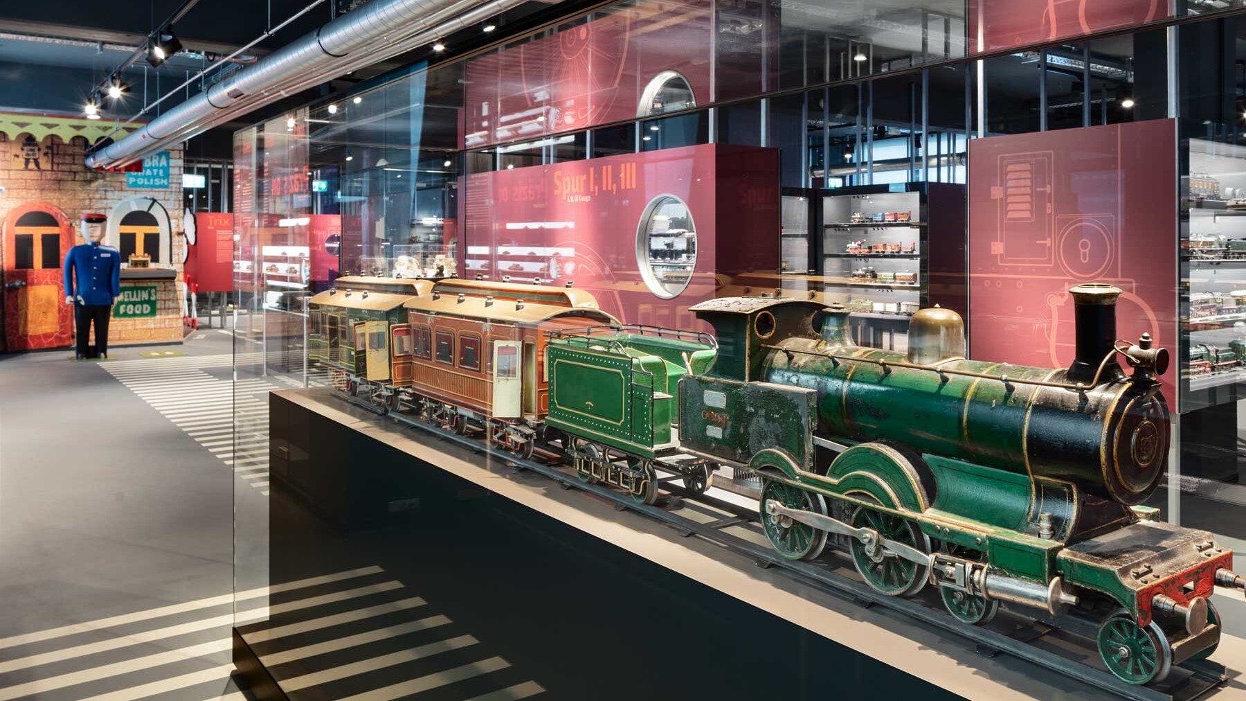 Grüne Modell-Lok mit zwei Waggons in einem Schaukasten im Museum Märklineum.