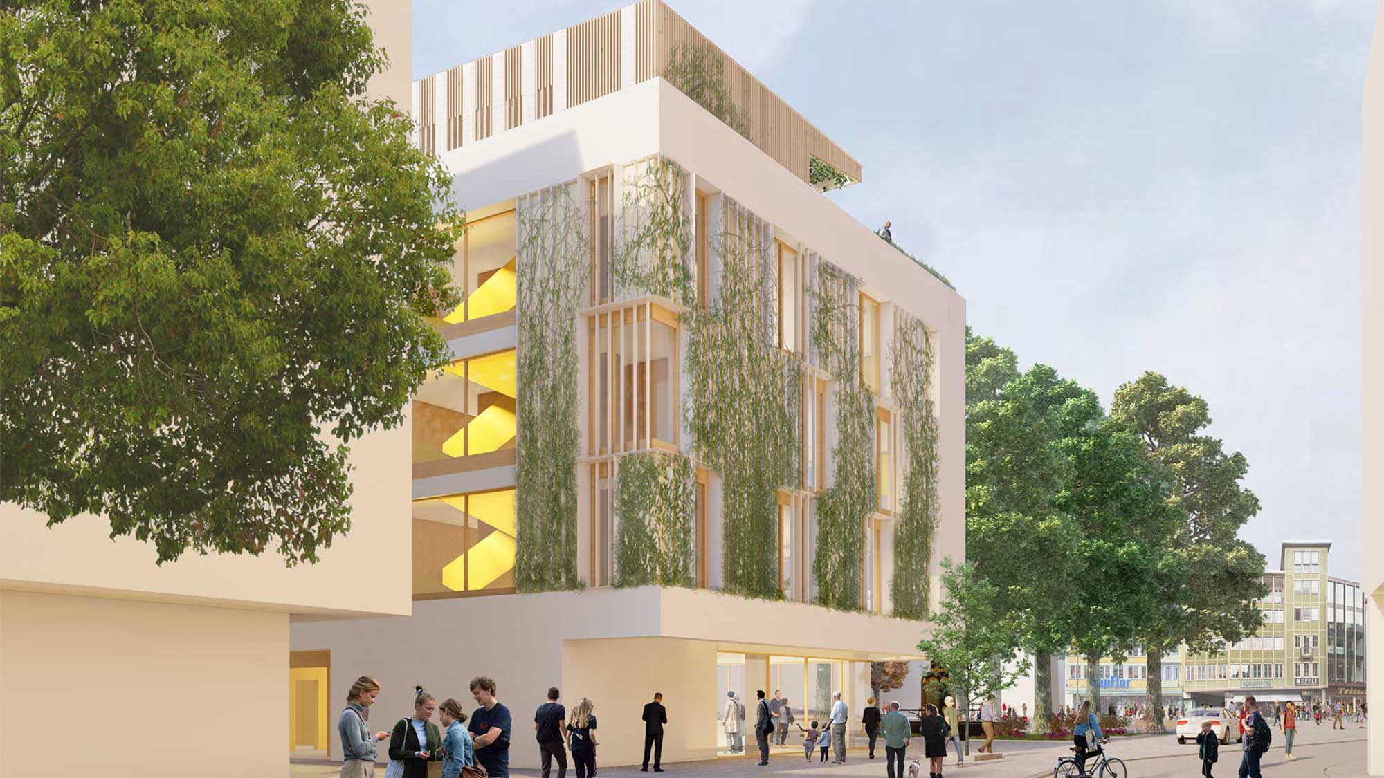 Blick auf das mehrstöckige Gebäude mit begrünter Fassade. Die Bäume vor dem Gebäude sind Grün, und einige Personen tummeln sich um das Gebäude.