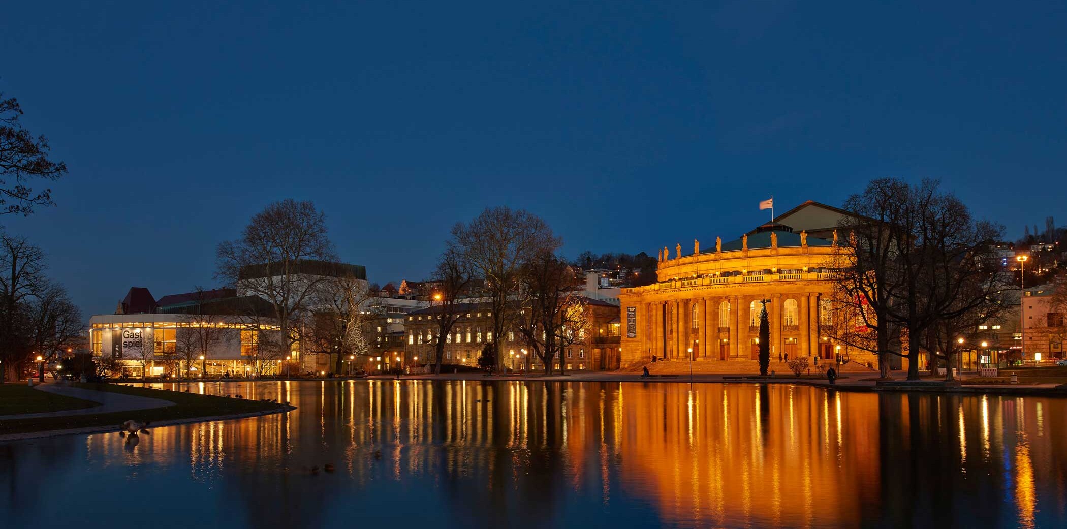 Schauspielhaus und Opernhaus Stuttgart, 2015, Aufnahme des Opernhaus bei Nacht. Weiter hinten links im Bild befindet sich das Schauspielhaus. Im Eckensee spiegeln sich die Lichter beider Gebäude.